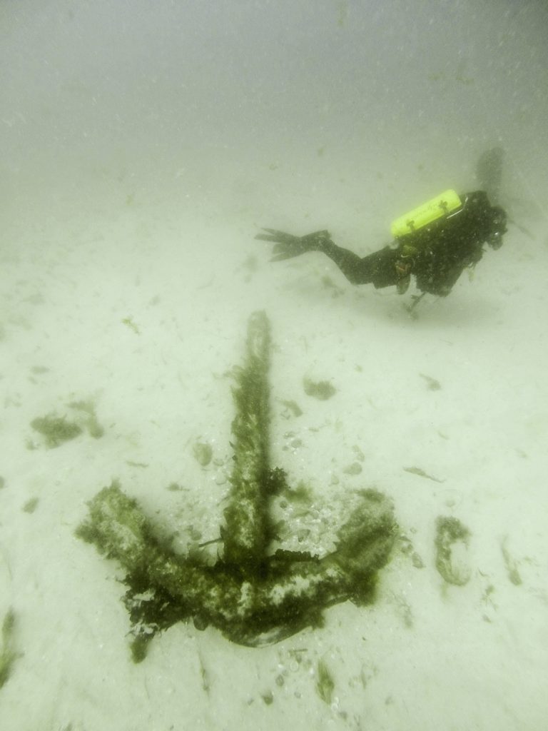 Diver visiting an iron anchor on the seabed
